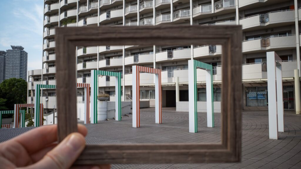 A man in a dark suit stands pensively before a blackboard filled with white question marks. His upward gaze and thoughtful expression reflect the search for purpose and clarity in choosing a career path aligned with personal identity.