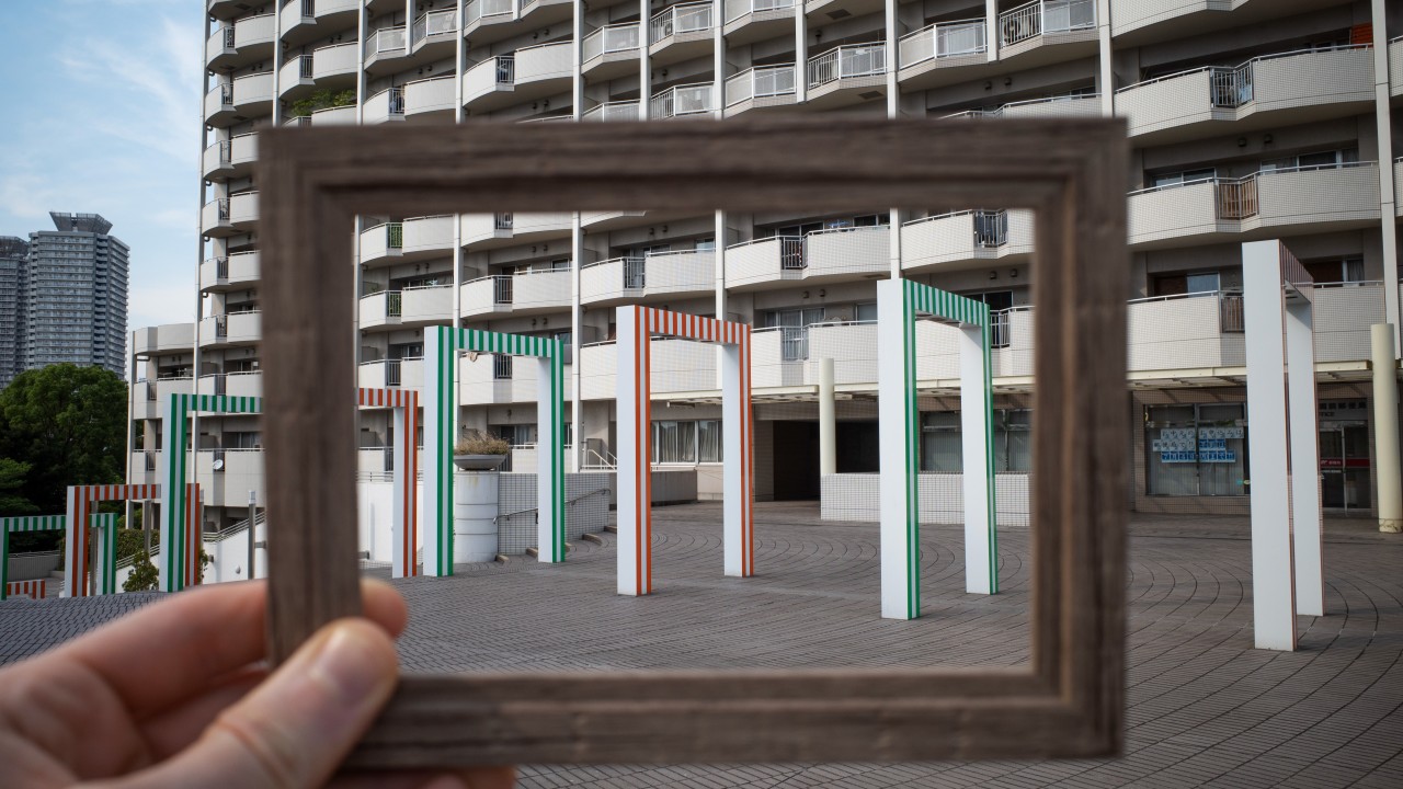 A man in a dark suit stands pensively before a blackboard filled with white question marks. His upward gaze and thoughtful expression reflect the search for purpose and clarity in choosing a career path aligned with personal identity.